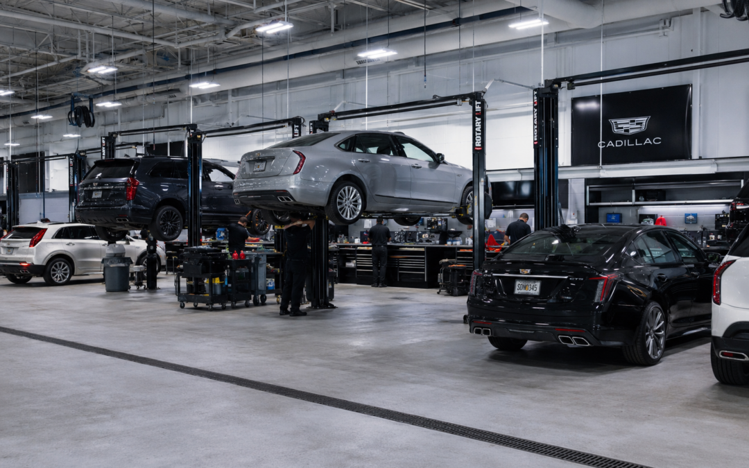 Full Cadillac dealership service bays with multiple vehicles, lifts and factory-trained technicians at work.