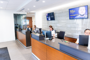 Service advisors assisting customers inside a modern Cadillac dealership service department.
